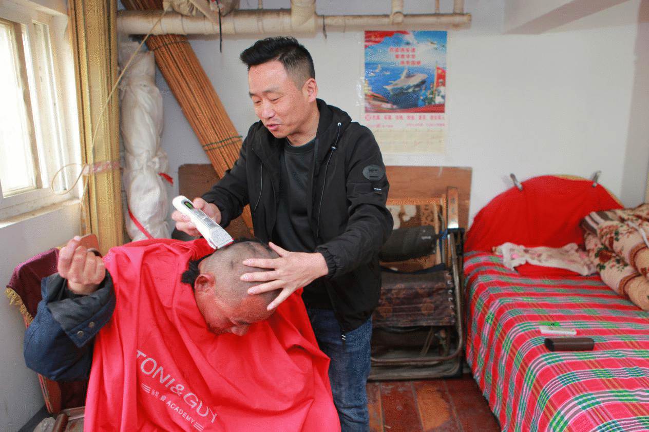 图为胡之勤在姚道广家义务理发。