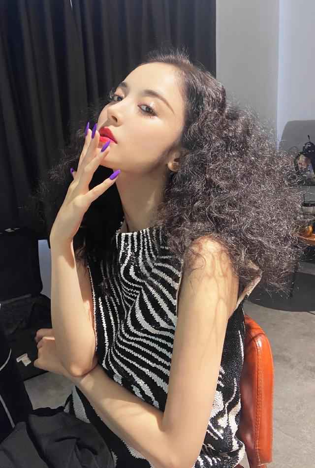古力娜扎身穿斑马条纹上衣，爆炸头搭配紫色指甲，轻松美出国际范